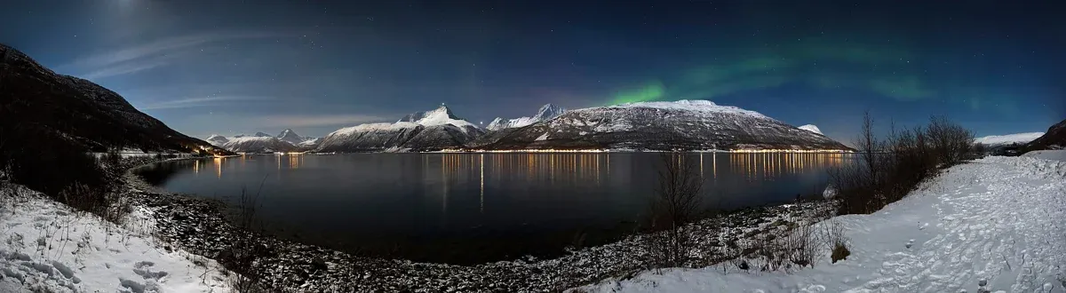 Northern lights over Storfjorden and the Lyngen Alps in moonlight, the landscape around Tromso reindeer sledding