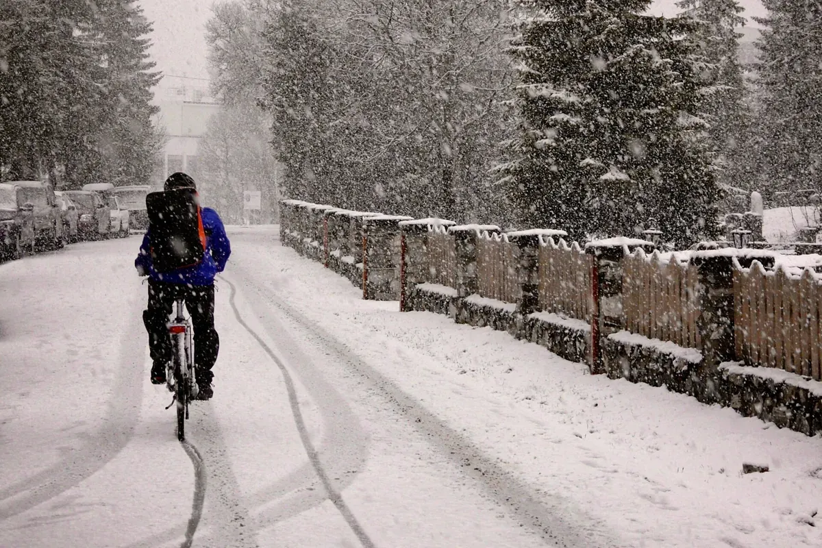 A cyclist riding through heavy snowfall in Tromsø, the weather to dress for before Tromso reindeer sledding